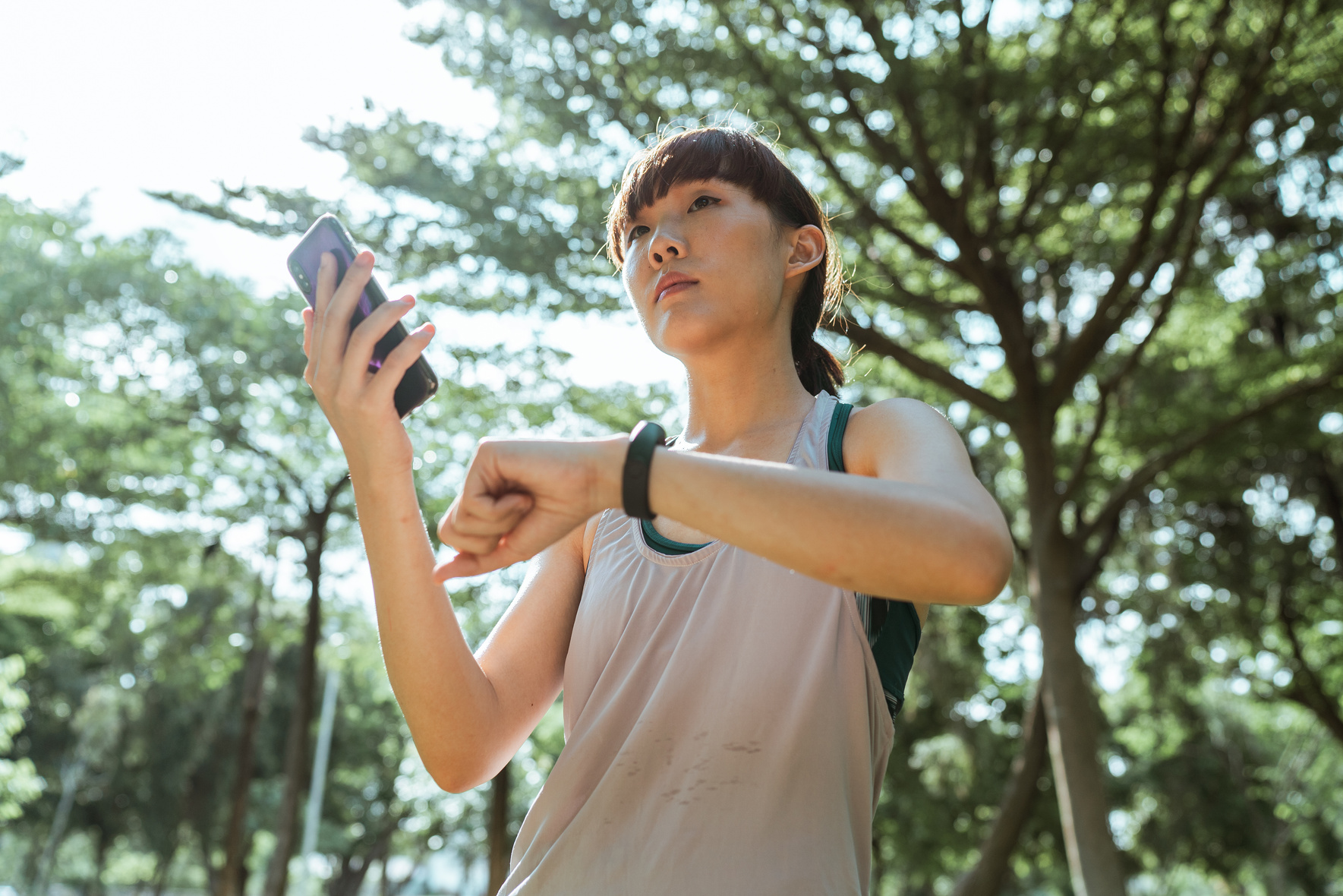 Young ethnic woman connecting smartphone and smart watch